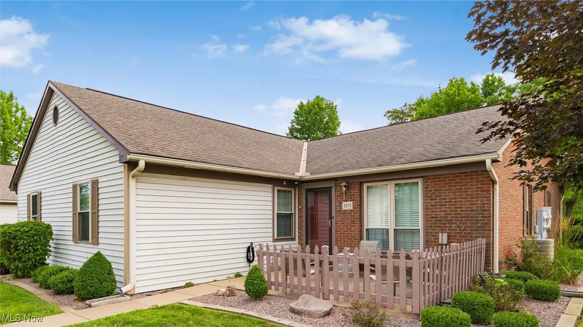 Ranch-style house featuring a shingled roof and brick siding
