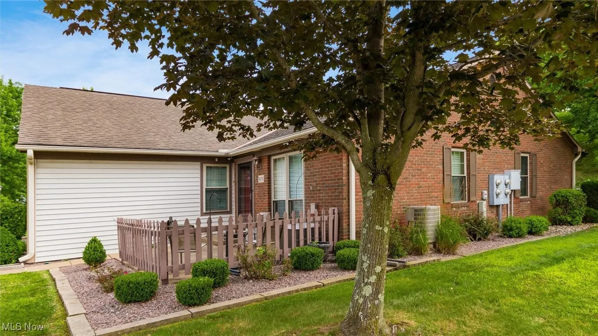 View of front of home with a front yard, brick siding, and roof with shingles