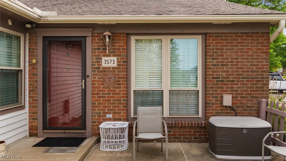 Doorway to property with brick siding and a shingled roof
