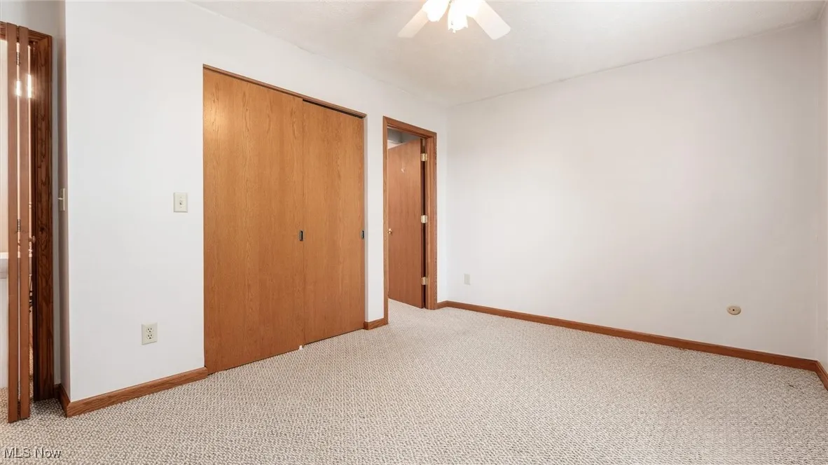 Unfurnished bedroom with a closet, light colored carpet, and ceiling fan