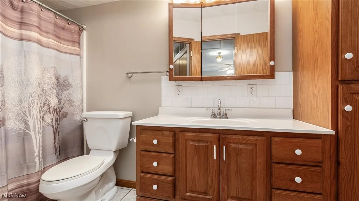 Full bath featuring vanity, tasteful backsplash, and curtained shower