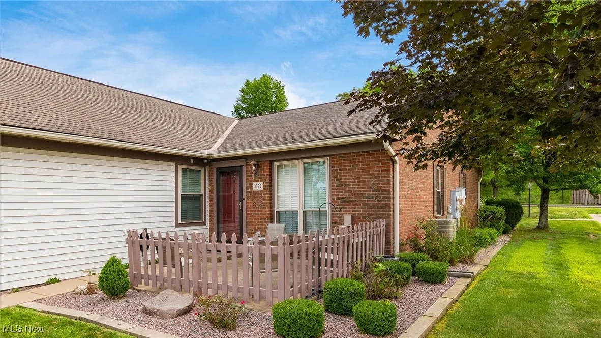 Property entrance with roof with shingles, a yard, and brick siding
