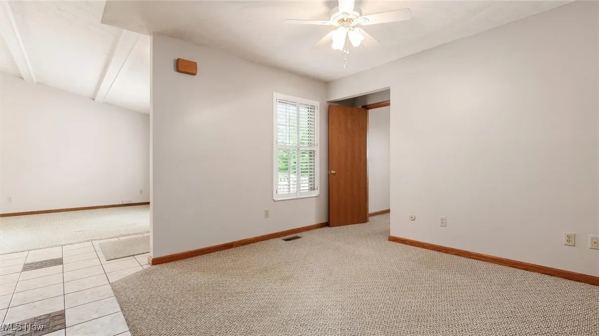 Carpeted empty room with ceiling fan and baseboards
