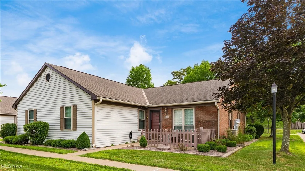 Ranch-style home with roof with shingles, a front yard, and brick siding