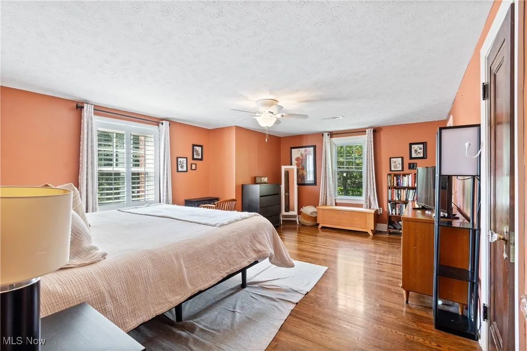 Bedroom with multiple windows, wood finished floors, and a textured ceiling