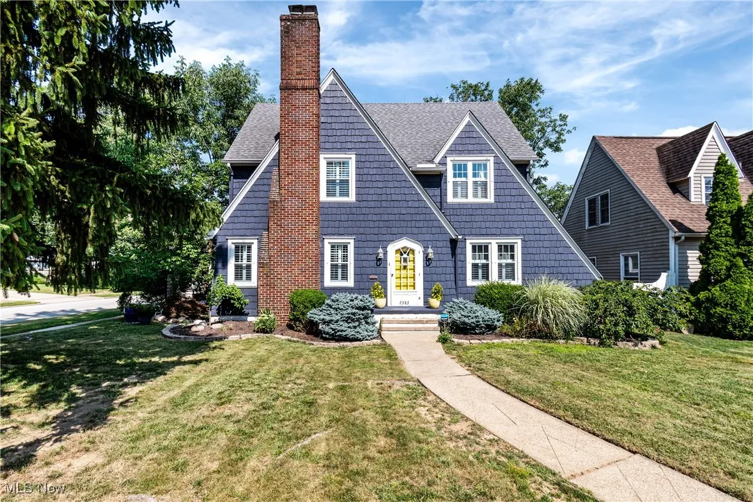 View of front of house featuring a chimney, a front lawn, and roof with shingles