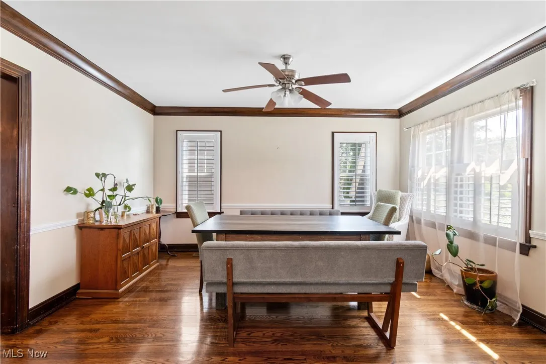 Dining area featuring ornamental molding, dark wood-style floors, and a ceiling fan