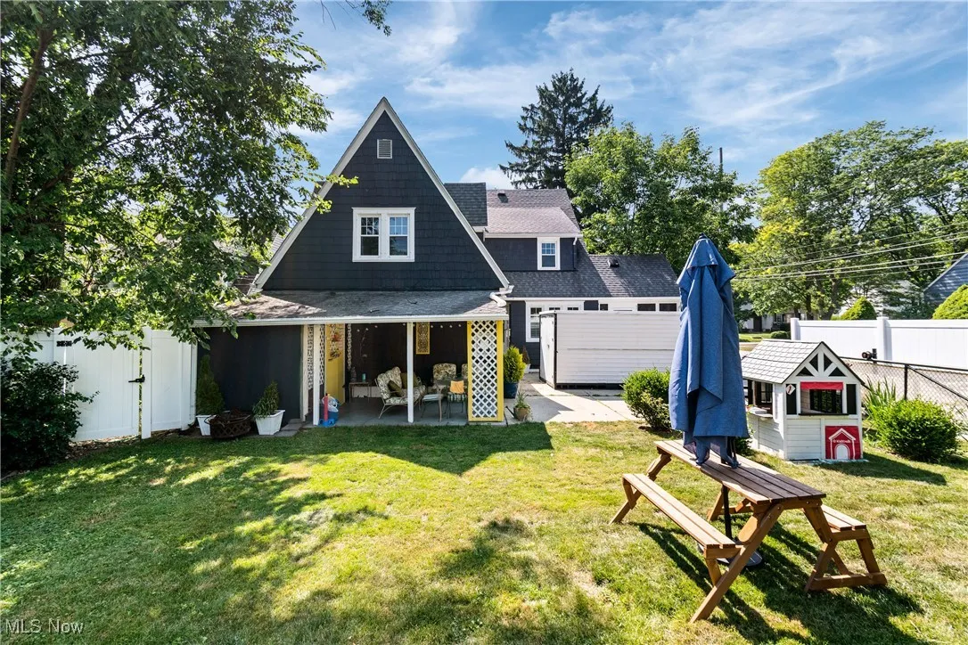 Back of house with a patio, an outbuilding, and roof with shingles