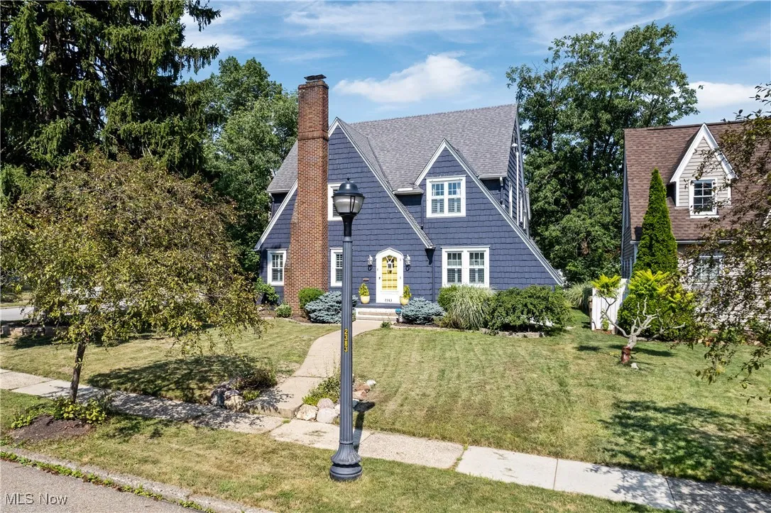 View of front of house featuring a chimney, a front lawn, and roof with shingles