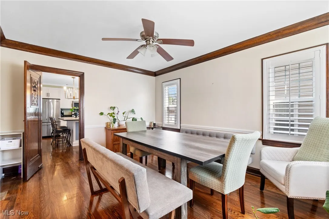 Dining area featuring dark wood-type flooring, ornamental molding, ceiling fan, and a chandelier