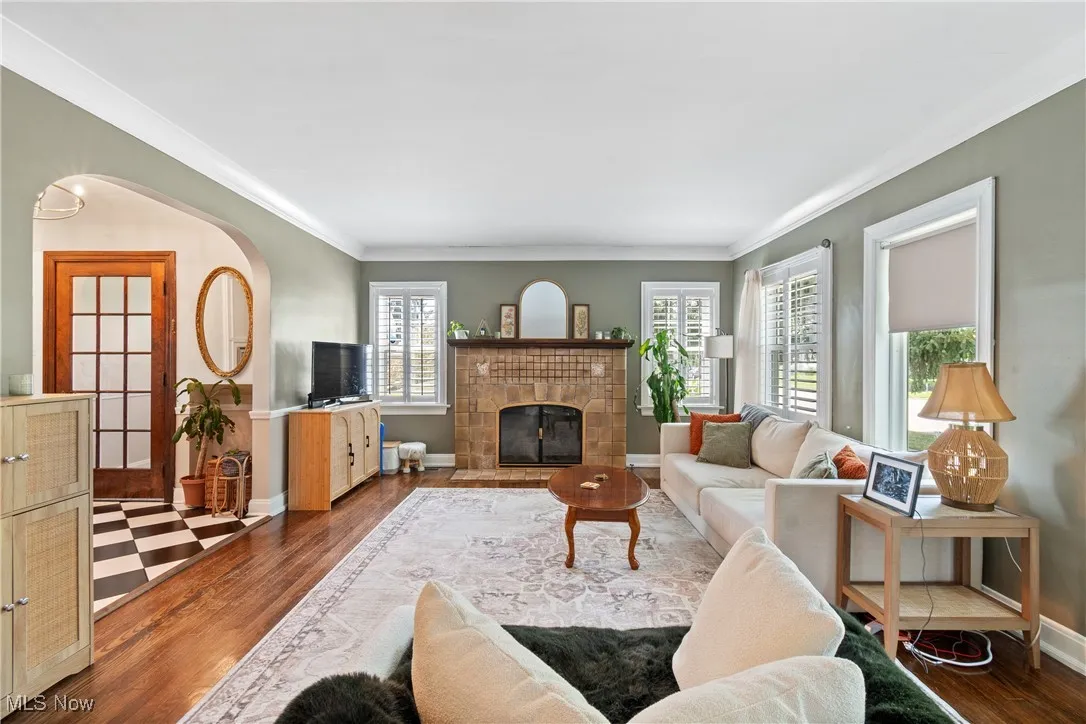 Living area featuring crown molding, dark wood-style floors, and a tile fireplace