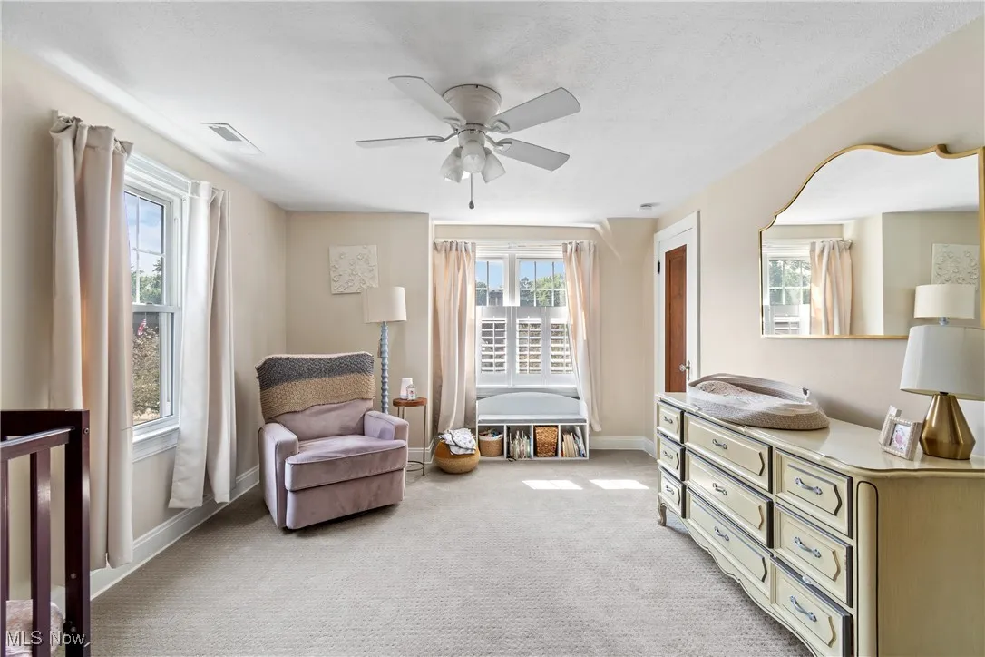 Sitting room with ceiling fan, plenty of natural light, and carpet floors