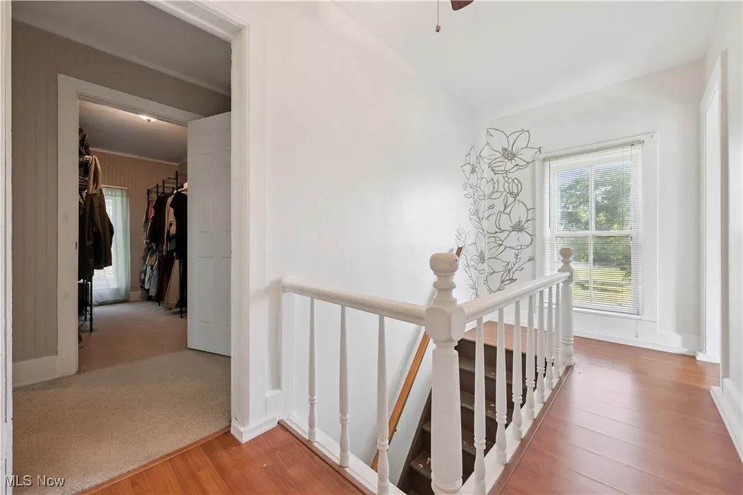 Corridor featuring an upstairs landing and light wood finished floors
