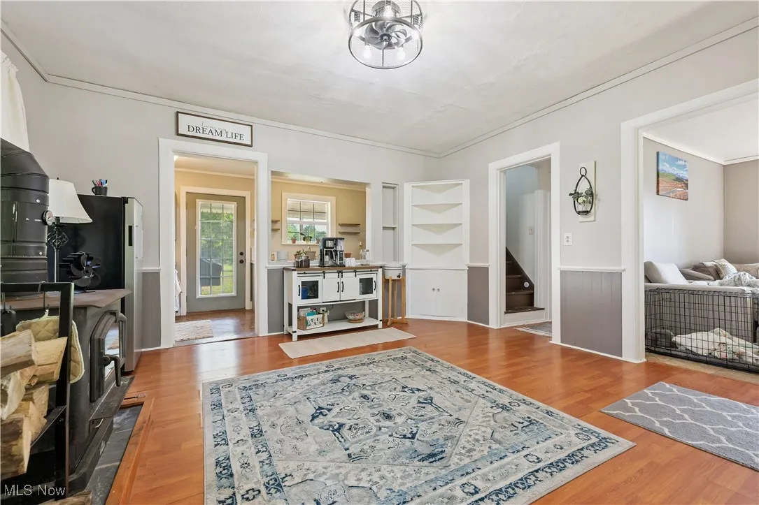 Dining room with built in features, wood look floors, stairs, and crown molding