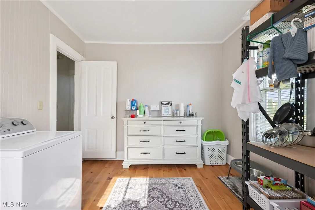 Laundry room featuring washer / dryer, crown molding, and light wood-style floors