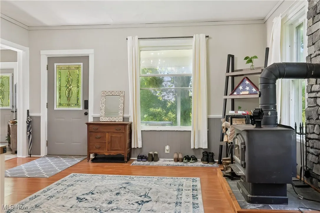 Office space featuring a wood stove, ornamental molding, wood look floors, plenty of natural light, and a wainscoted wall