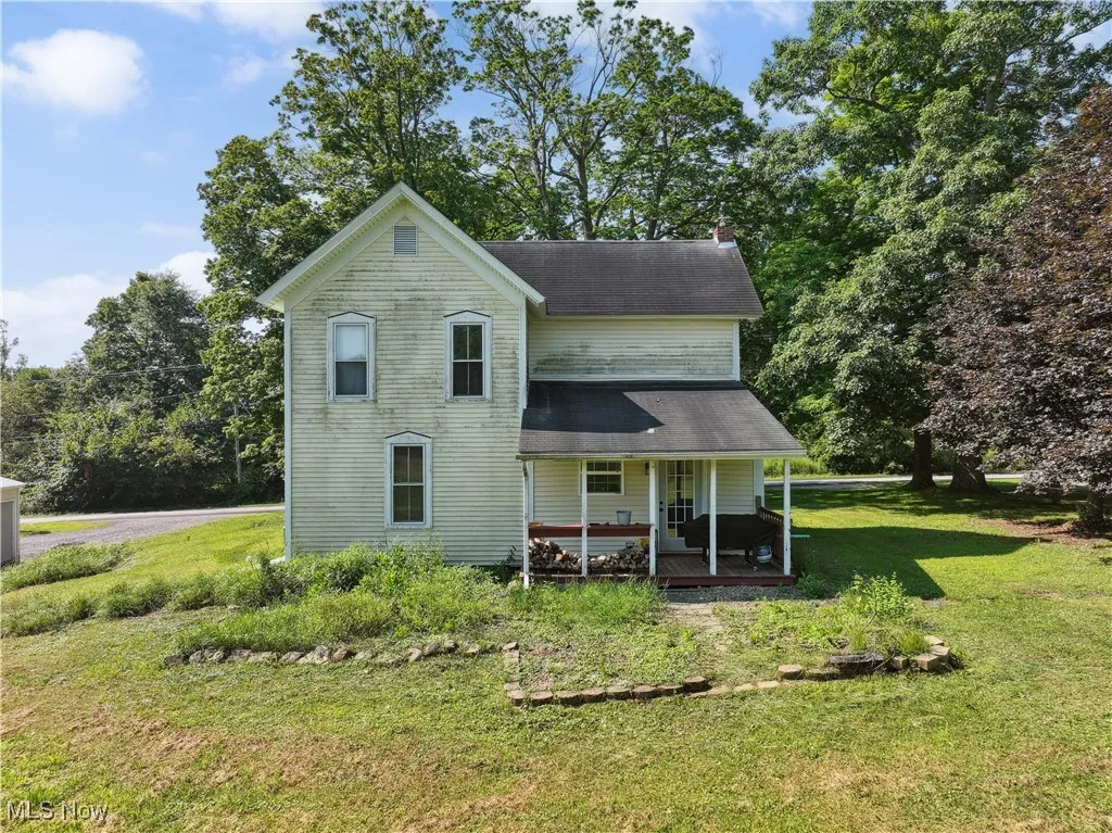 Rear view of property featuring covered porch and a yard
