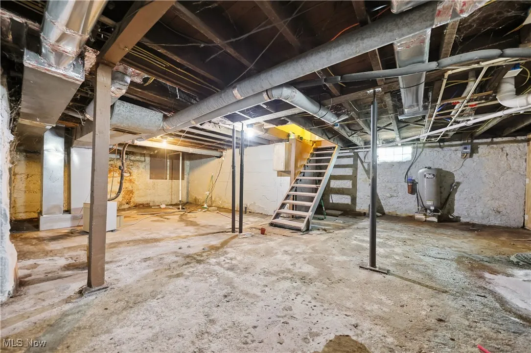 Unfinished below grade area featuring stairway and a water pressure tank