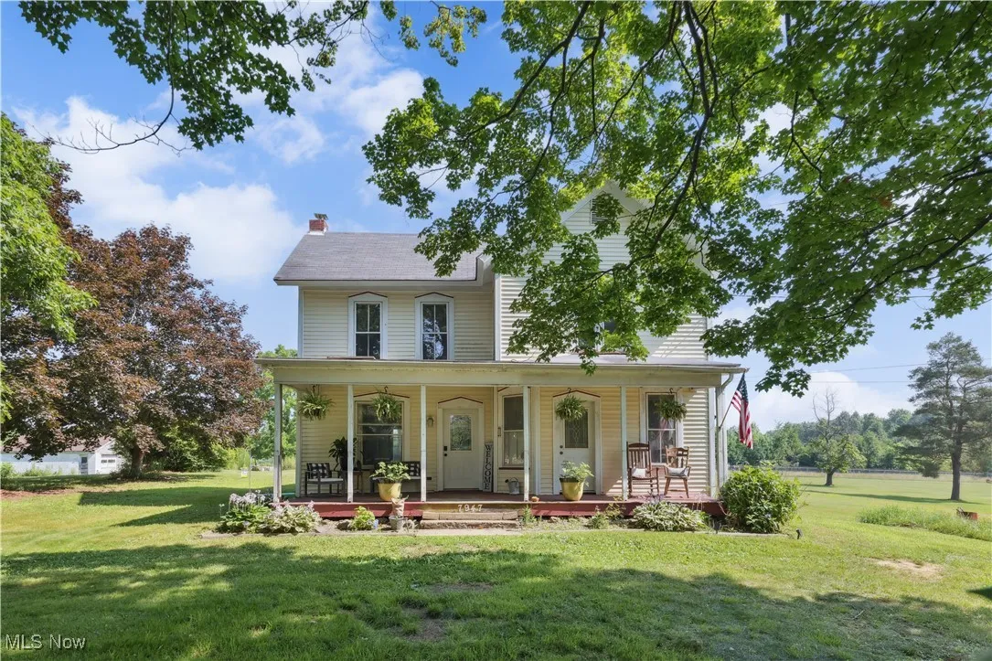 View of front of house with covered porch, a front lawn, and a chimney