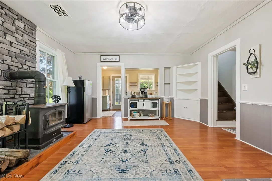 Dining room featuring a wood stove, wood finished floors, built in features, plenty of natural light, and crown molding