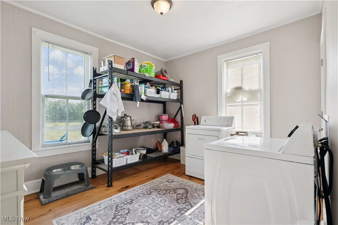 Laundry area featuring washer and clothes dryer, ornamental molding, and light wood-type flooring