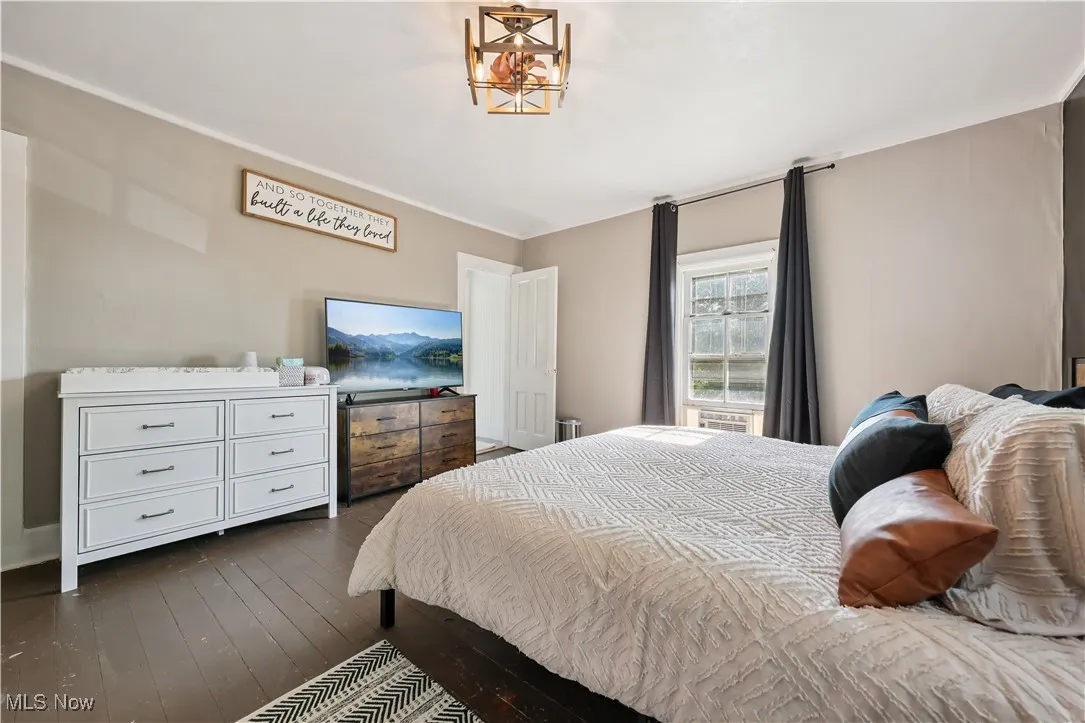 Bedroom with dark wood-type flooring and a chandelier