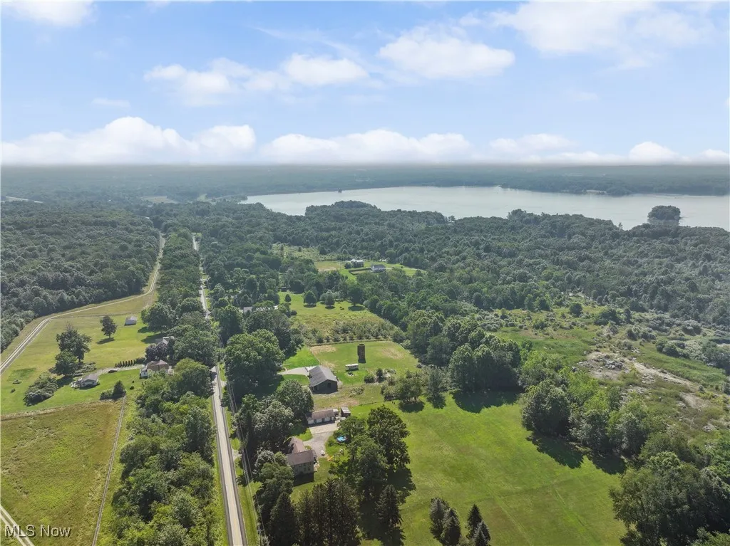 Drone / aerial view of a nearby body of water and a heavily wooded area