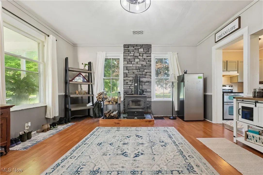 Dining room with a wood stove, wood look floors, and crown molding