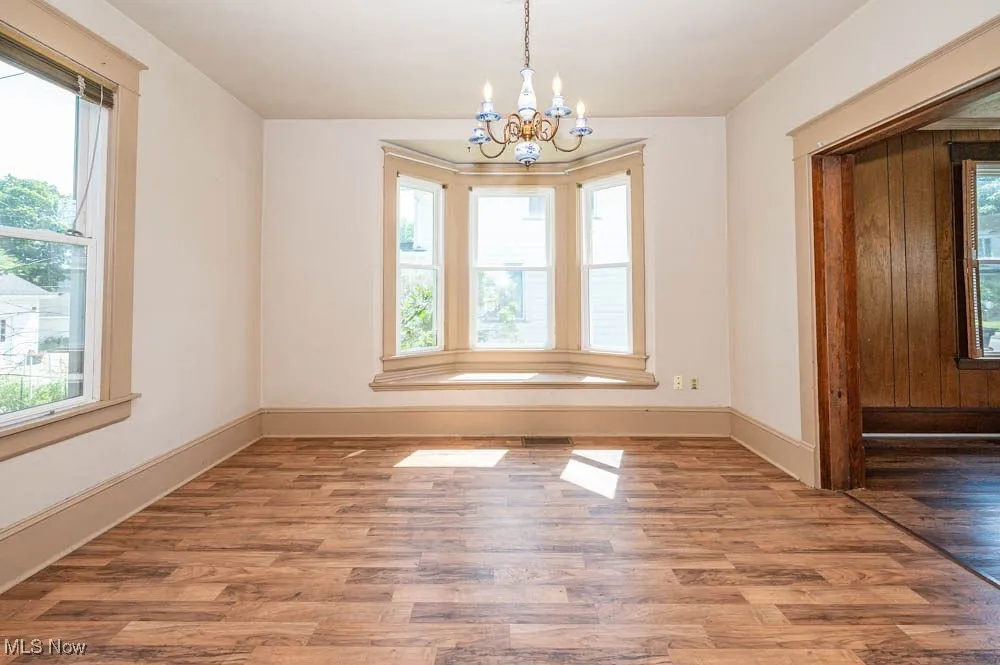 Dining room featuring healthy amount of natural light, a chandelier, and wood finished floors