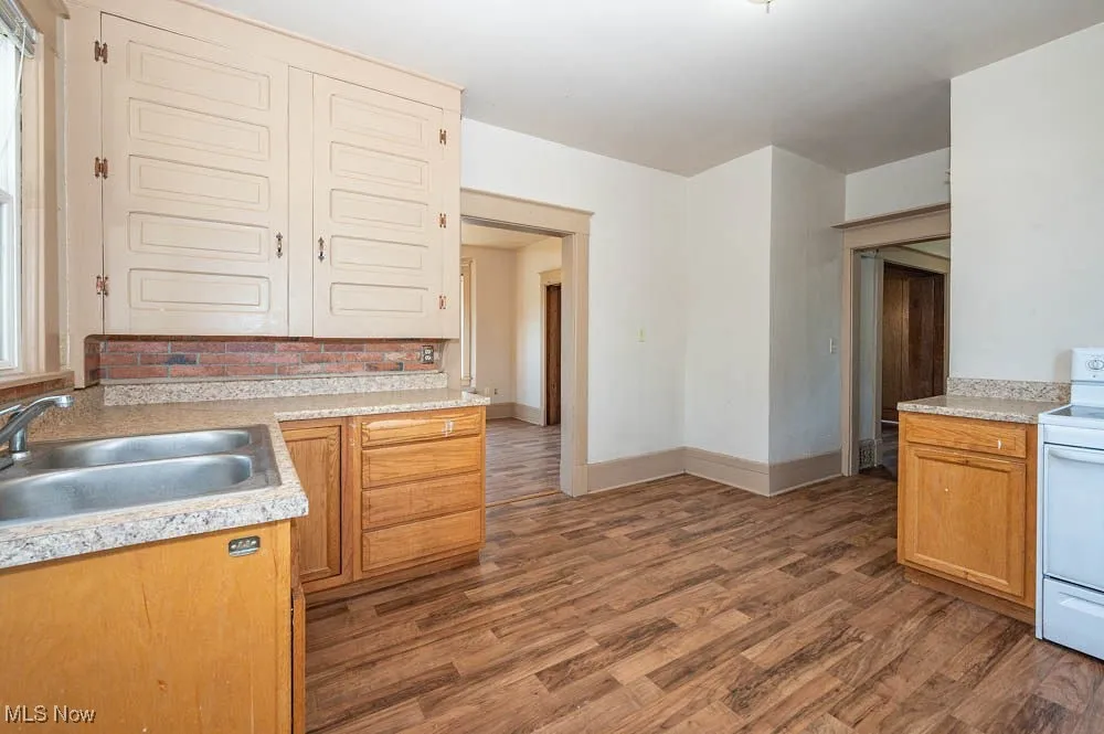 Kitchen featuring white electric stove, dark wood-style flooring, and light countertops