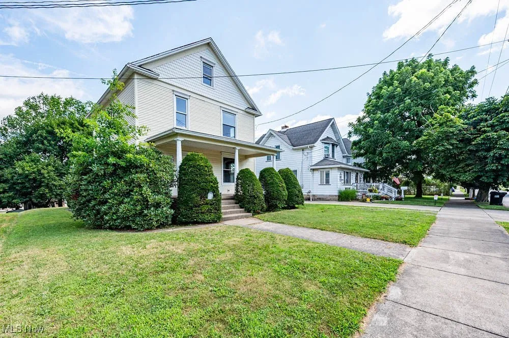 American foursquare style home with a front lawn and covered porch