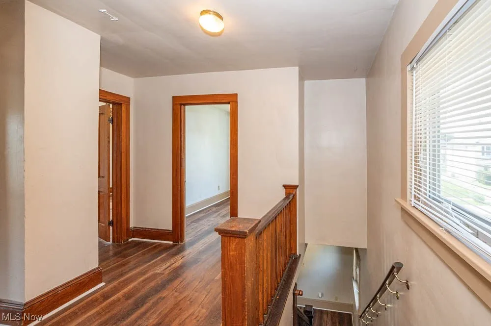 Corridor featuring an upstairs landing and dark wood-style flooring