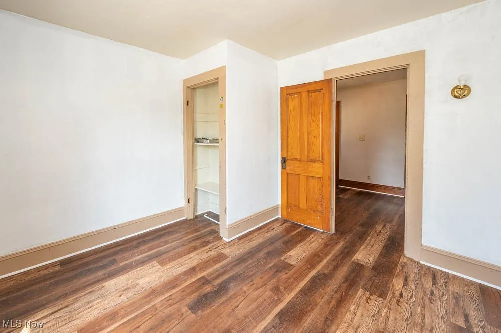 Empty room with dark wood-style floors and baseboards