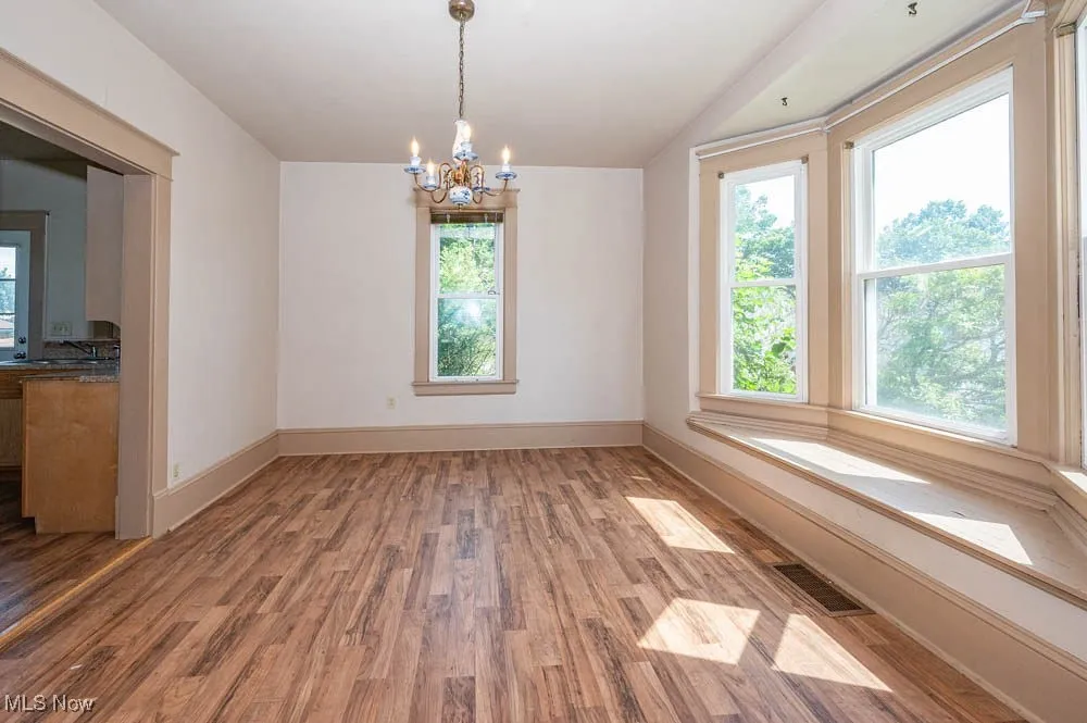 Dining room with plenty of natural light, wood finished floors, and a chandelier