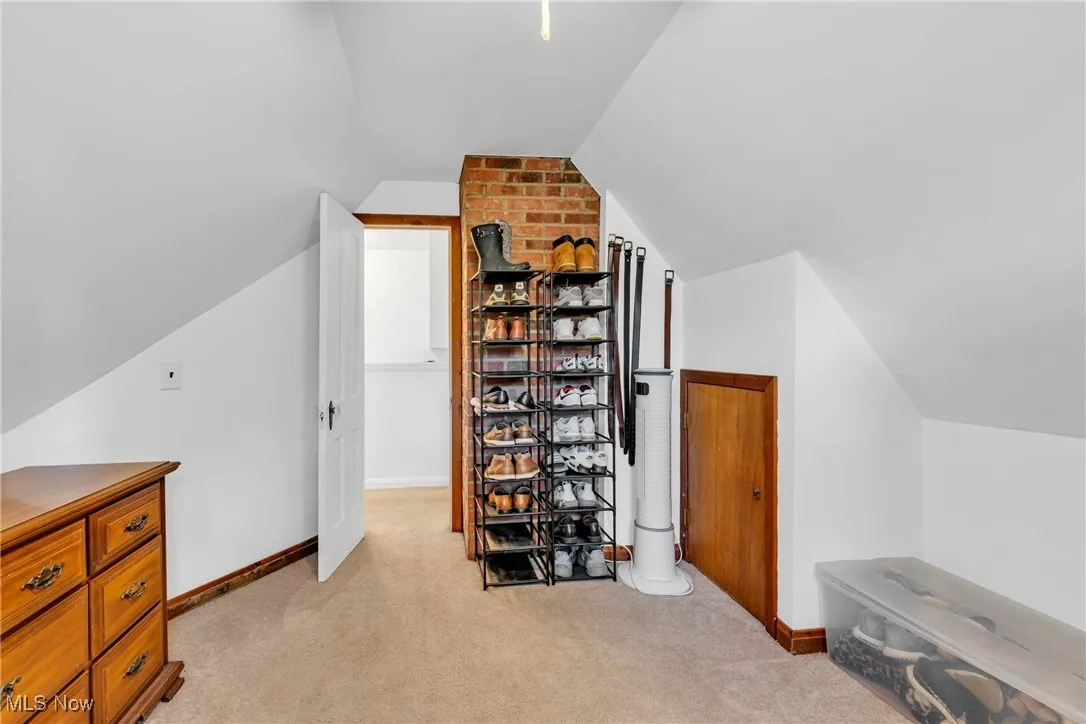 Additional living space with vaulted ceiling and light colored carpet
