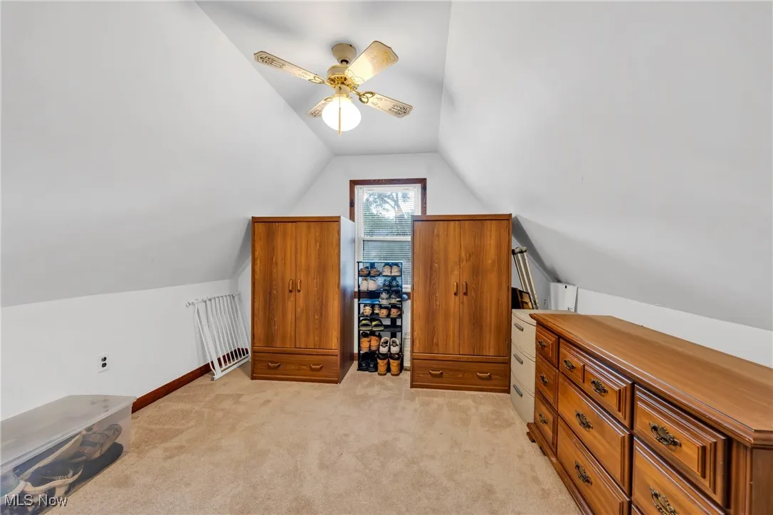 Additional living space with light carpet, vaulted ceiling, and ceiling fan