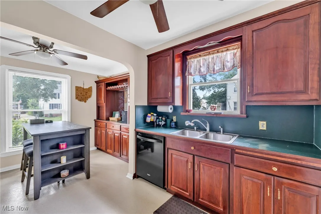 Kitchen featuring a ceiling fan, open shelves, dishwasher, and dark countertops