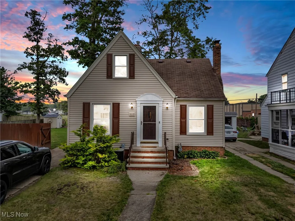 View of front of house featuring a lawn, a chimney, roof with shingles, and entry steps