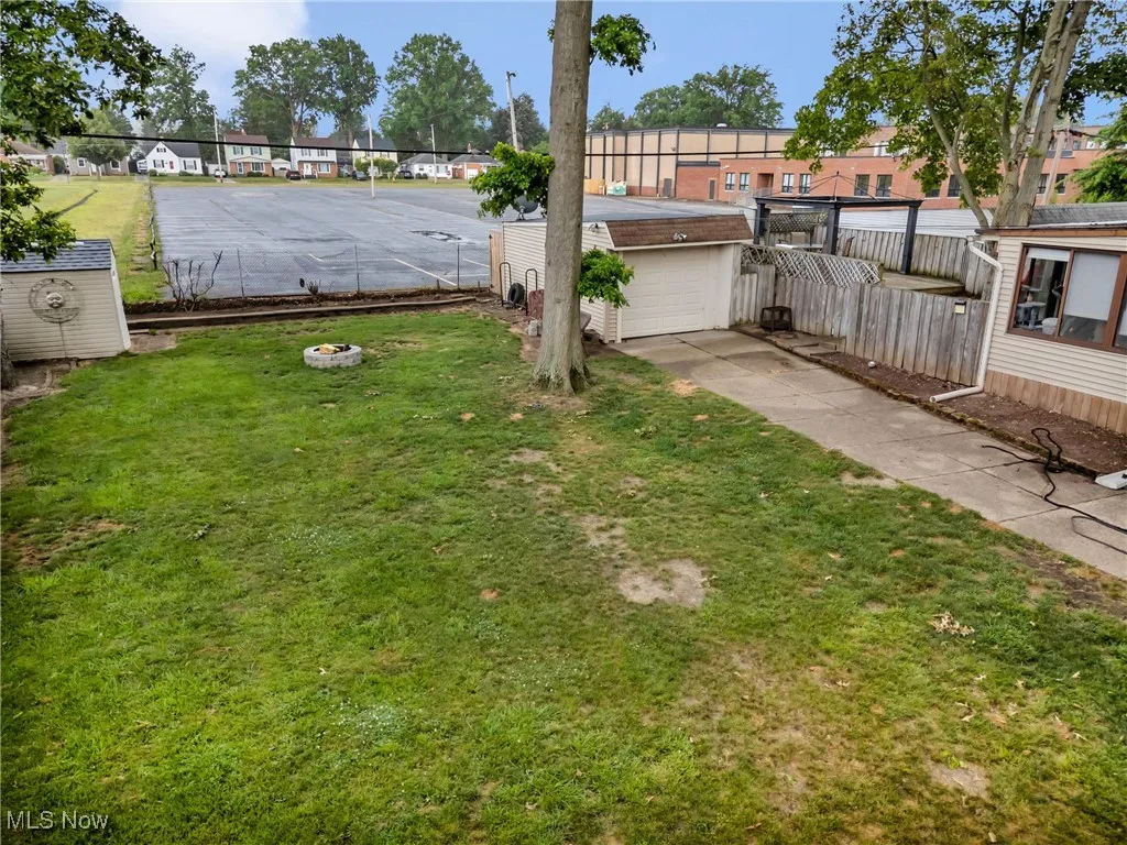 View of yard featuring a garage, driveway, an outbuilding, and a residential view