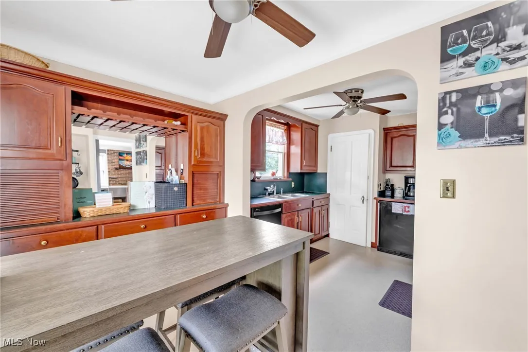 Kitchen featuring ceiling fan, arched walkways, wine cooler, a kitchen breakfast bar, and dishwasher