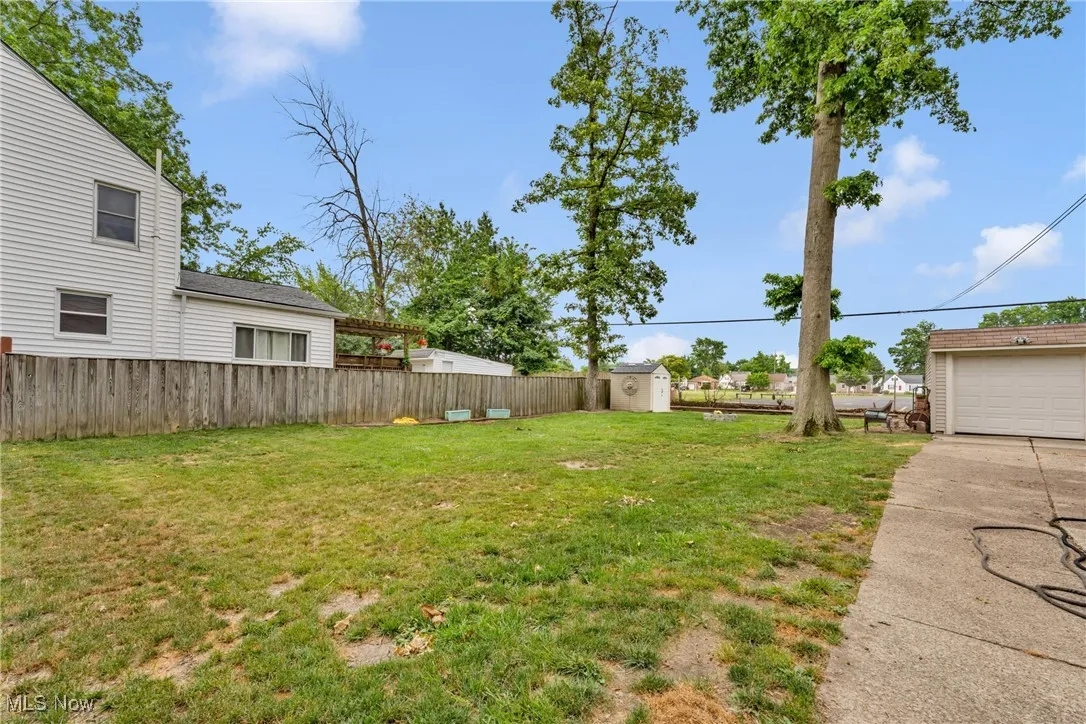 Fenced backyard featuring a storage unit