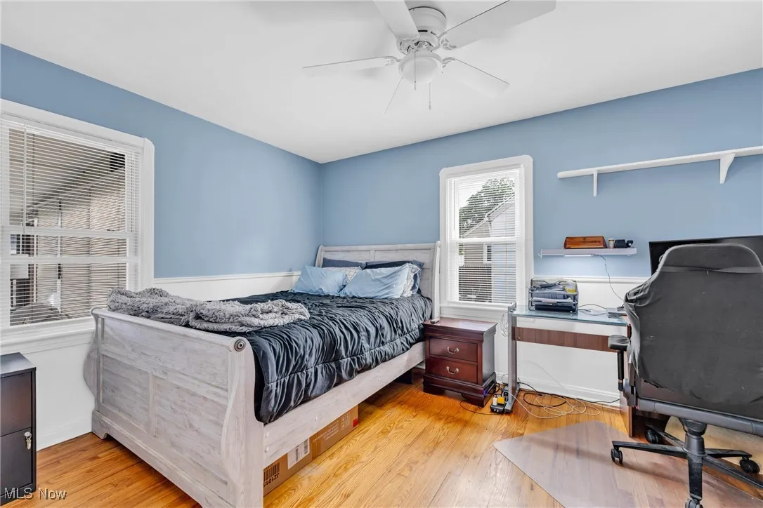 Bedroom with light wood finished floors, an office area, and a ceiling fan