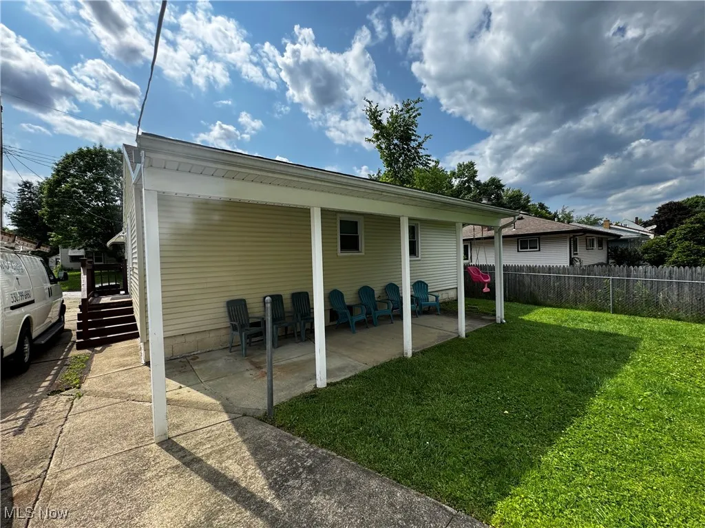 Back of house featuring an attached carport, concrete driveway, and a patio