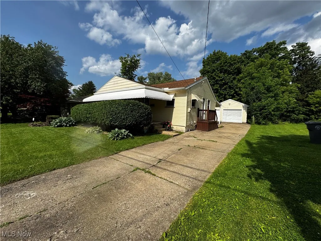 View of side of home featuring a detached garage, an outdoor structure, and a yard