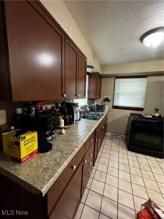 Kitchen featuring range, light tile patterned floors, and a textured ceiling