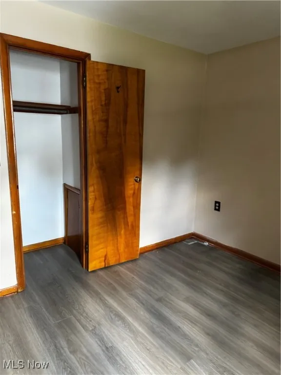 Unfurnished bedroom with wood finished floors and a closet
