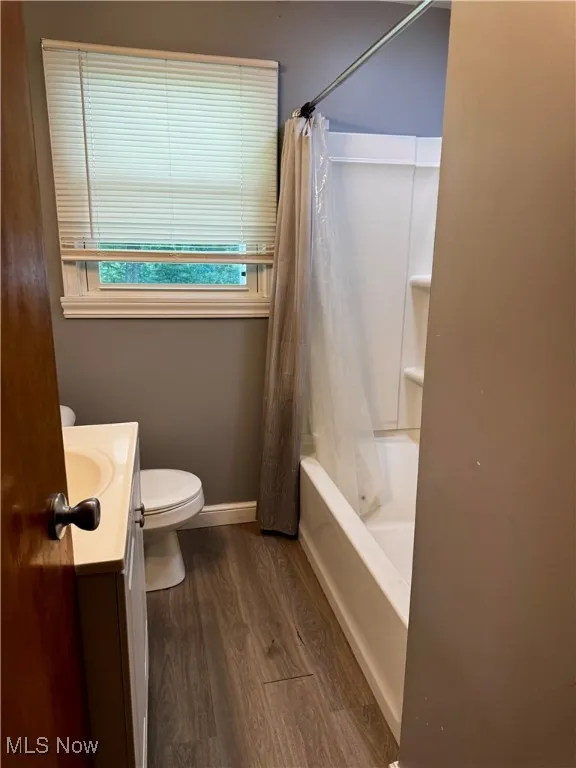 Bathroom with vanity, wood finished floors, and shower / bathtub combination with curtain