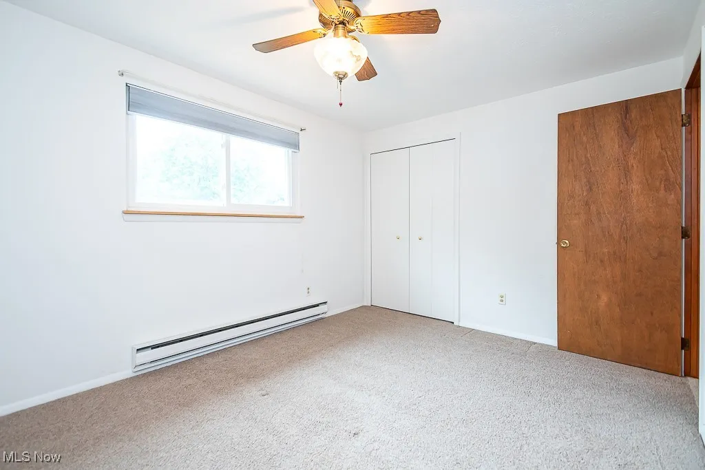 Unfurnished bedroom featuring heating, carpet flooring, a closet, and a ceiling fan