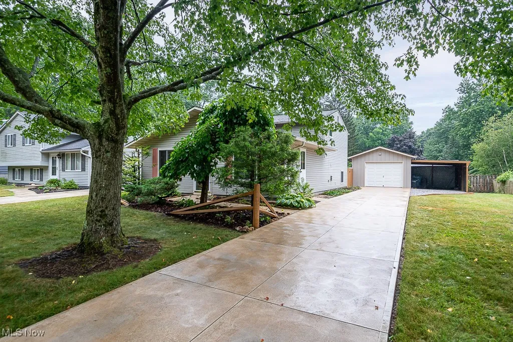 View of front facade featuring concrete driveway, an outbuilding, a front lawn, and a detached garage
