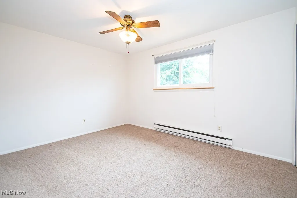 Carpeted bedroom featuring a baseboard radiator and a ceiling fan